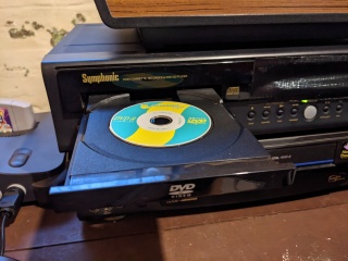 A blue and yellow mini-DVD in a full-size DVD playertray.